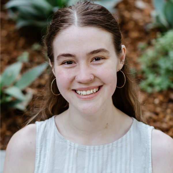 A professional headshot of Cassidy Belk smiling with plants in the background.