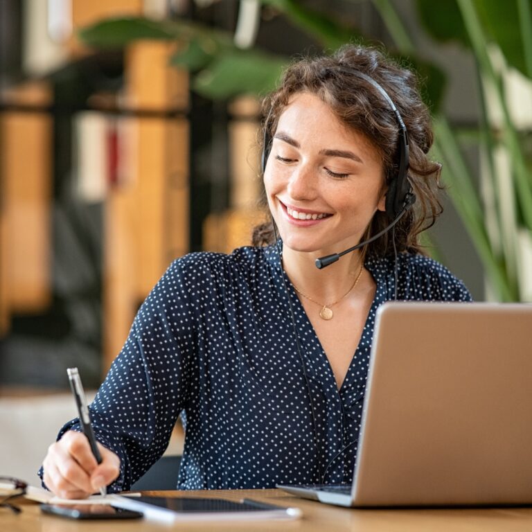 a service agent smiles while talking on a headset.