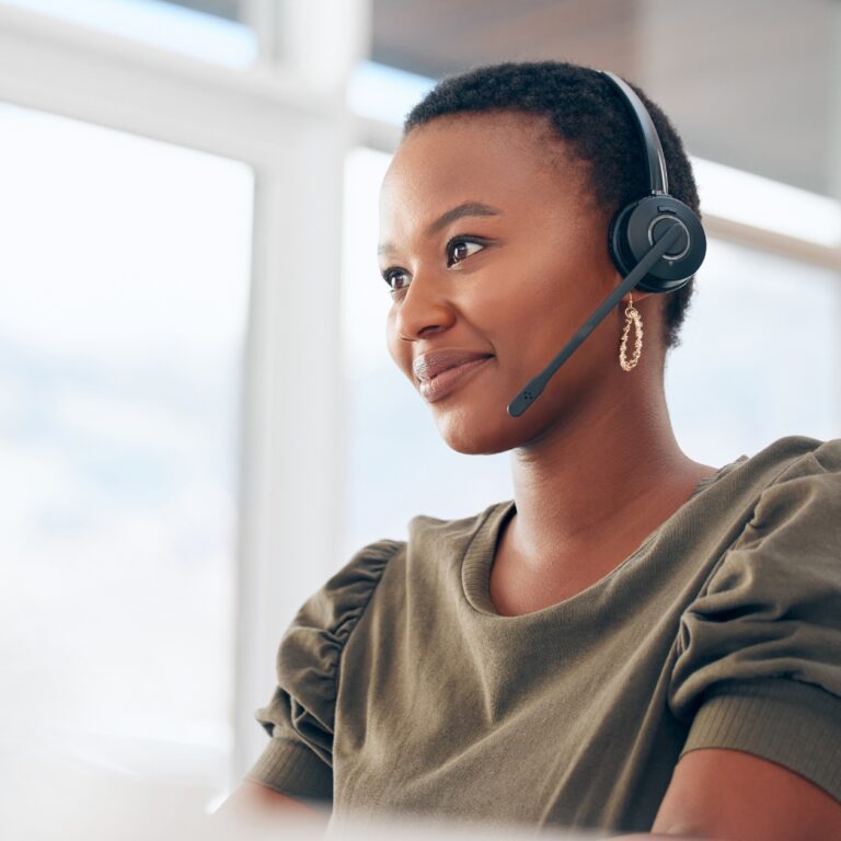 a young service representative smiles while wearing a headset.